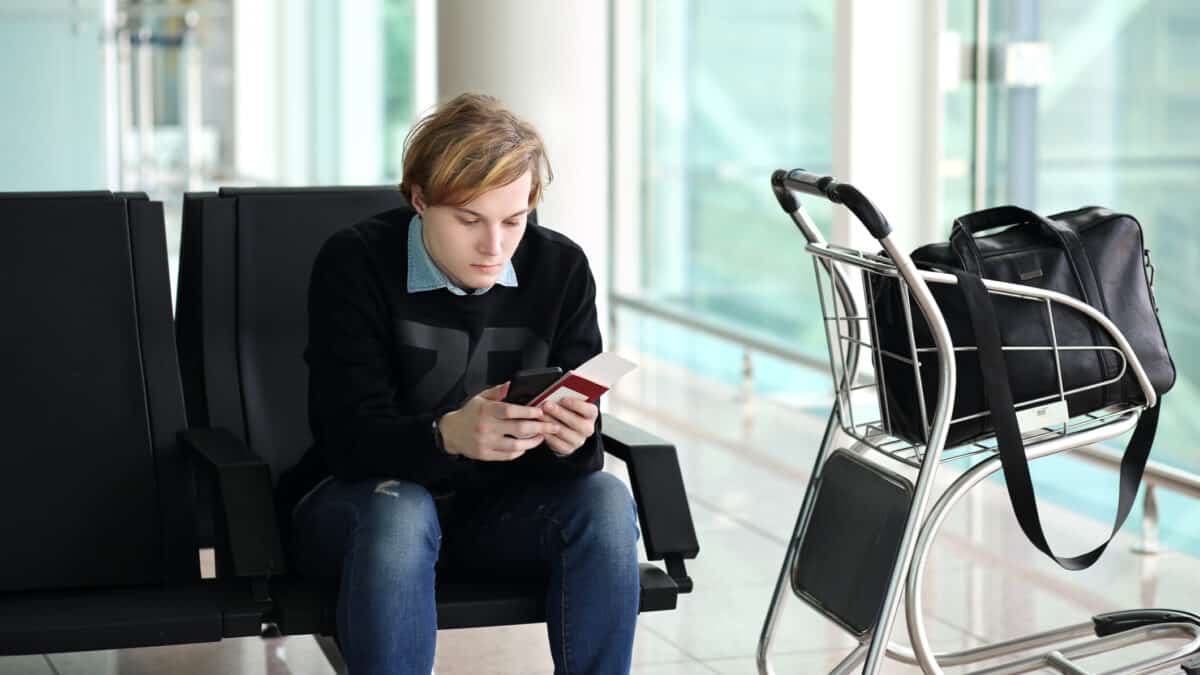 Man waiting for his flight and looking at his phone.