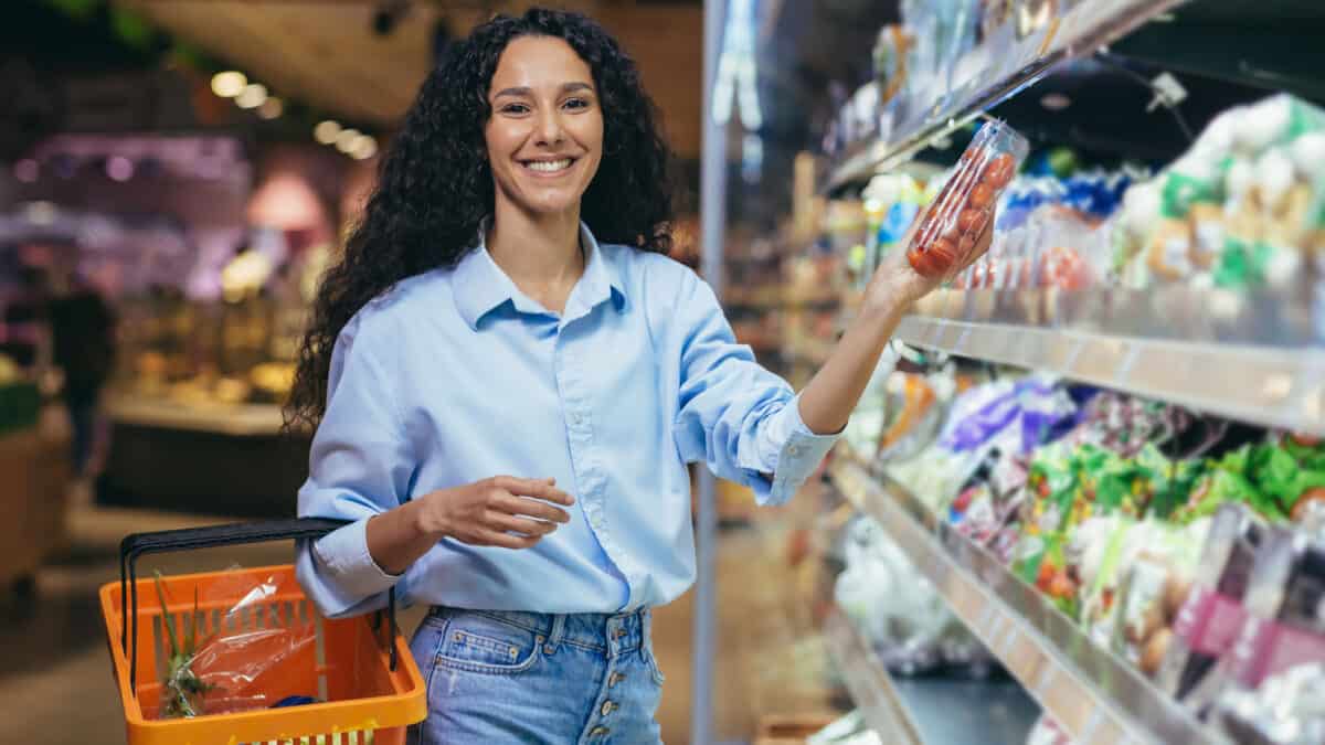 Woman chooses vegetables for dinner, smiling and looking at camera.