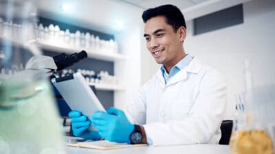 Happy, tablet or doctor in a laboratory with research results or positive feedback after medical data analysis. Smile, vaccine or healthcare worker reading or working on futuristic science innovation.