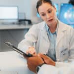 Research, collaboration and doctors working digital tablet, analysis and discussion of innovation cancer treatment. Healthcare, teamwork and planning by experts sharing idea and strategy for surgery.