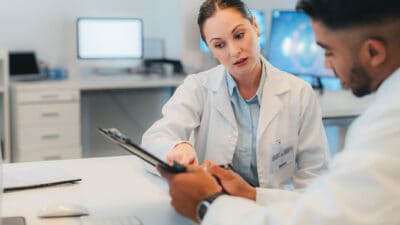 Research, collaboration and doctors working digital tablet, analysis and discussion of innovation cancer treatment. Healthcare, teamwork and planning by experts sharing idea and strategy for surgery.