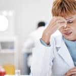 Scientist with headache, stress and fatigue with woman, overworked with overtime for science breakthrough. Medical research, scientific innovation and senior female, burnout and migraine in lab.