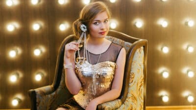 Elegant lady with make up wearing jewellery and sitting on a chair.