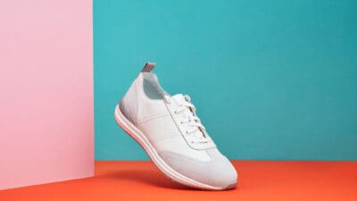 Men's sport sneaker or trainer on orange, green and pink background.