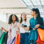 Happy friends holding shopping bags in a shopping mall.