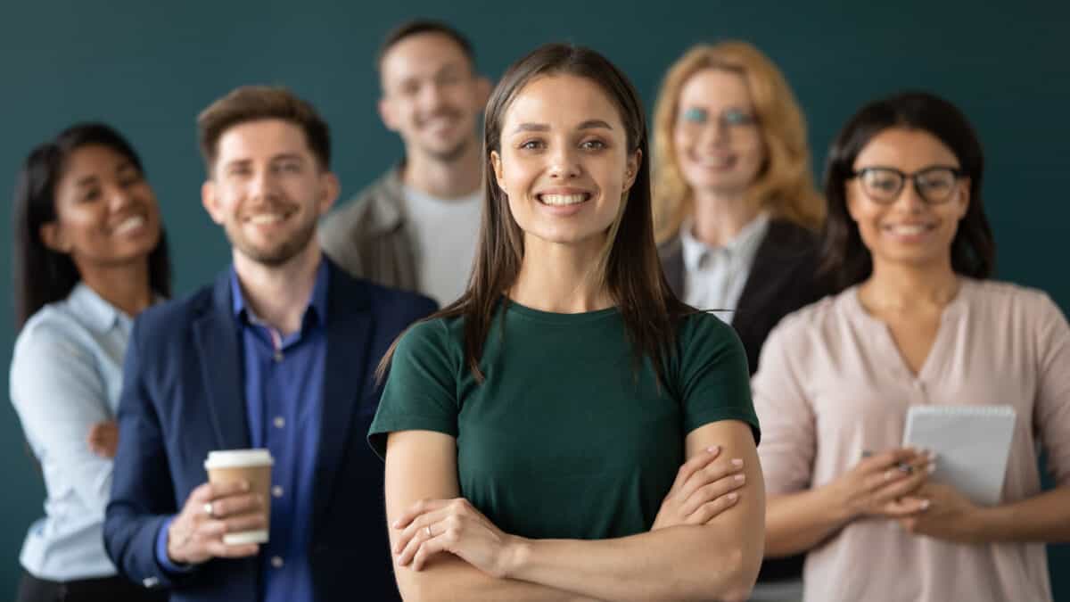 Close up portrait of happy businesswoman standing in front or leading her multi-ethnic corporate team.