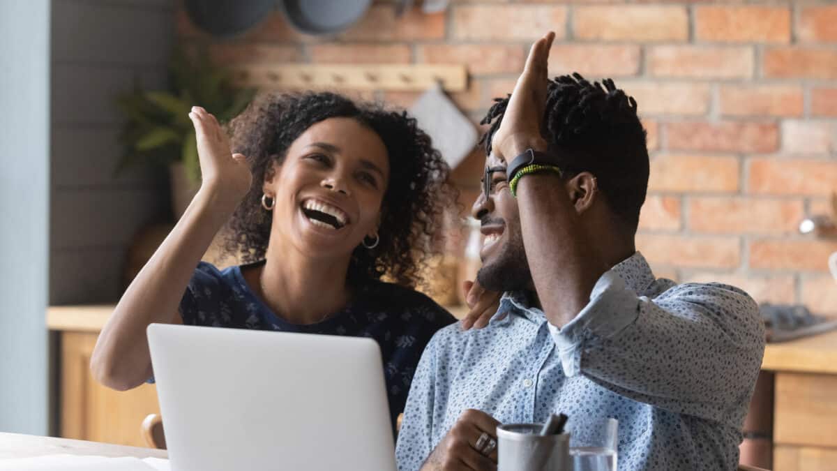 Emotional euphoric young woman giving high five to male partner, celebrating family achievement, getting bank loan approval, or financial or investing success.