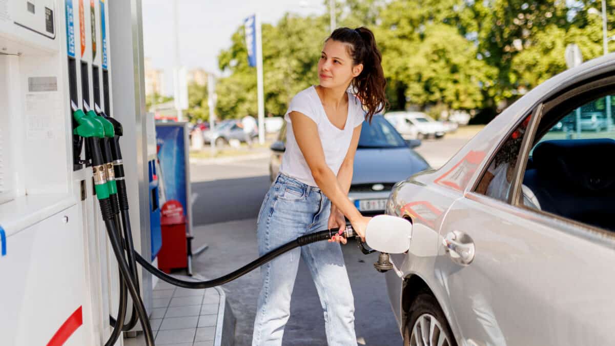 Woman refuelling the gas tank at fuel pump, symbolising the Ampol share price.