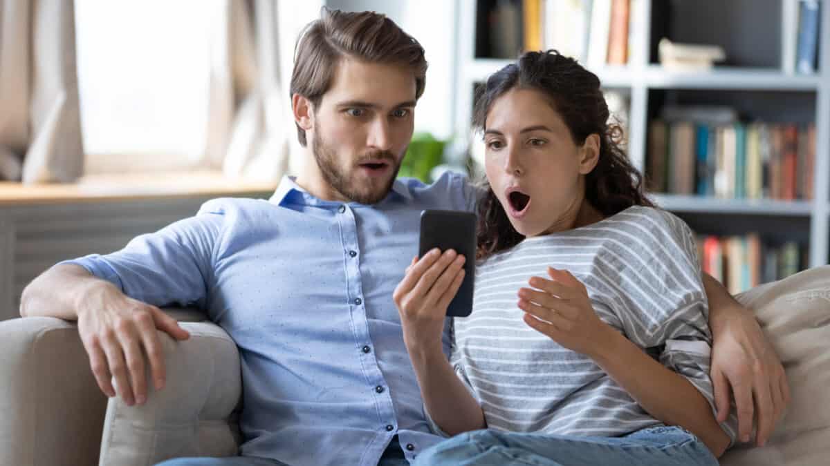 Couple looking at their phone surprised, symbolising a bargain buy.