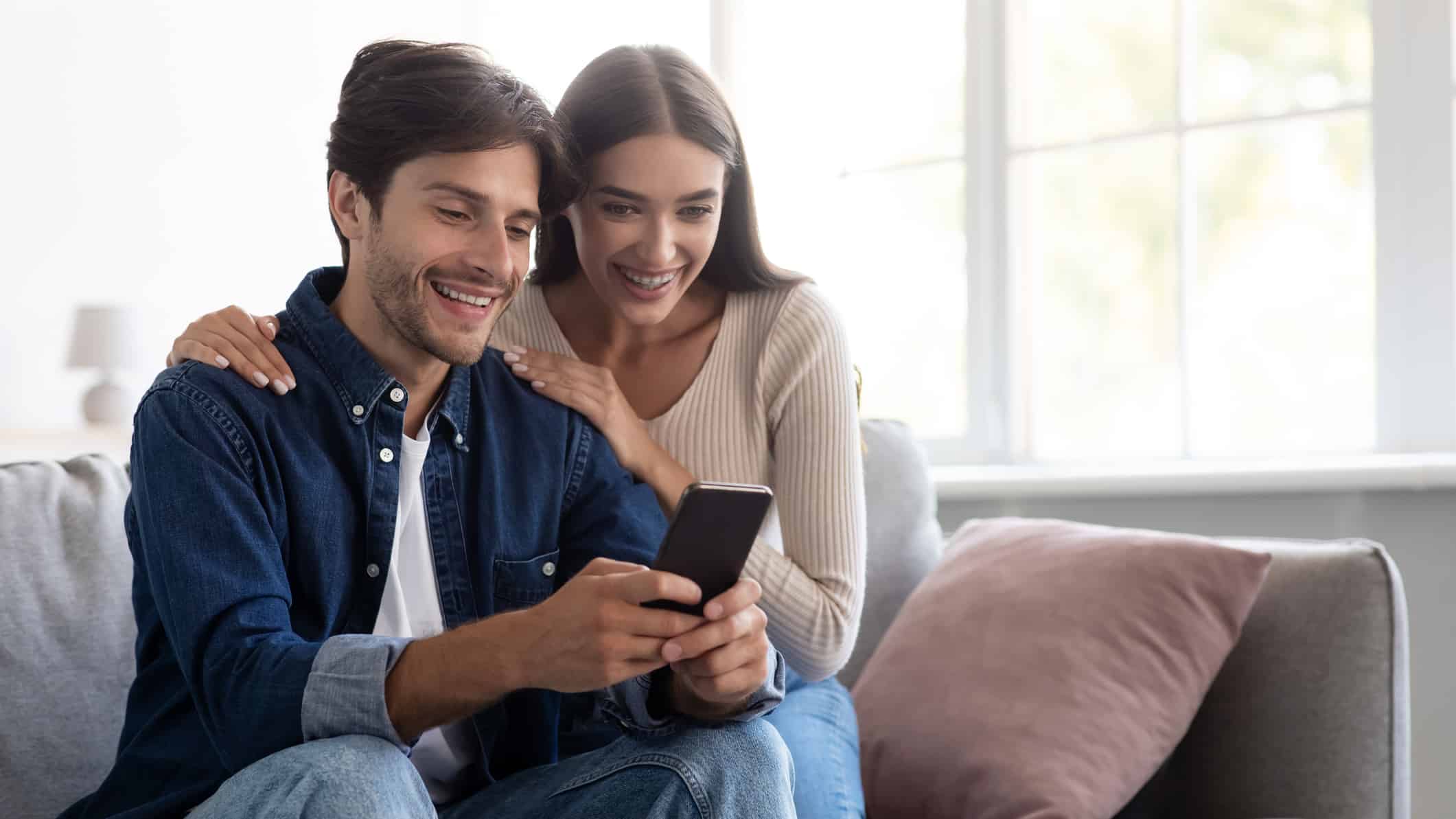 Smiling couple looking at a phone at a bargain opportunity.