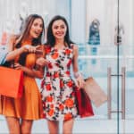 Two woman shopping and pointing at a bargain opportunity.