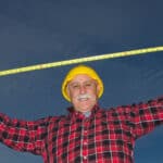 A builder or miner stretches a measure tape above his head, indicating something is big.