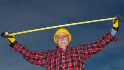 A builder or miner stretches a measure tape above his head, indicating something is big.