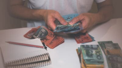 Person handling Australian dollar notes, symbolising dividends.