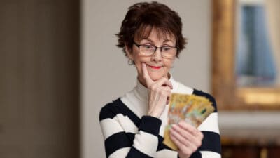 Woman with $50 notes in her hand thinking, symbolising dividends.