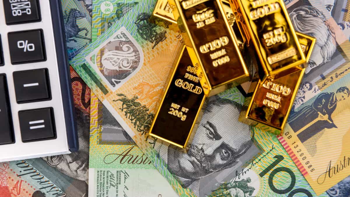 Calculator and gold bars on Australian dollars, symbolising dividends.
