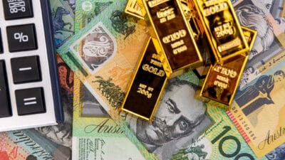 Calculator and gold bars on Australian dollars, symbolising dividends.