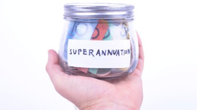 Superannuation written on a jar with Australian dollar notes.