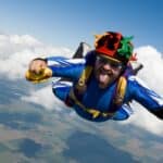 A skydiving man in a jester hat and carrying a burger and sauce, pokes out his tongue at the camera, indicating all is not lost when you're falling.