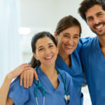 Three health professionals at a hospital smile for the camera.