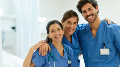 Three health professionals at a hospital smile for the camera.