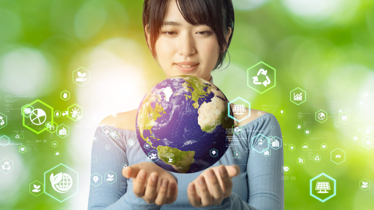 Image of a woman holding a model of earth on a green backdrop.