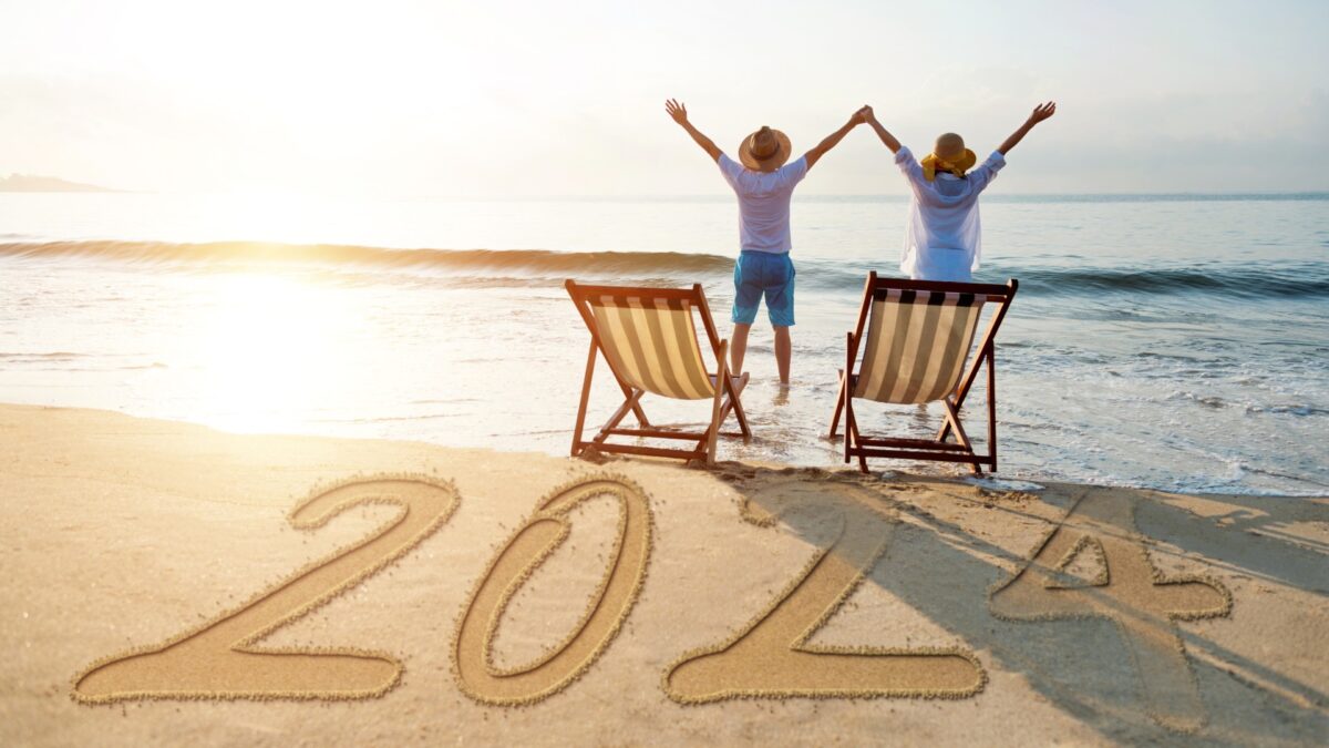 Two people on a beach jump out of their chairs to welcome the dawn of a new year, 2024