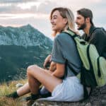 A young smiling couple out hiking enjoy a view from the top of the mountains.