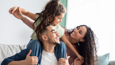 Smiling young parents with their daughter dream of success.