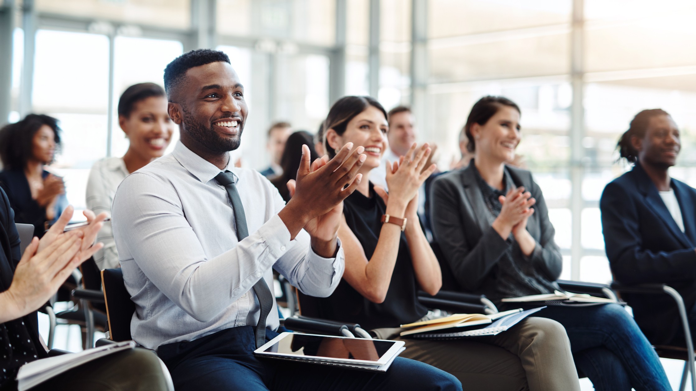 Happy shareholders clap and smile as they listen to a company earnings report.