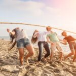 A group of six young people doing the limbo on a beach, indicating oversold shares that can not go any lower.