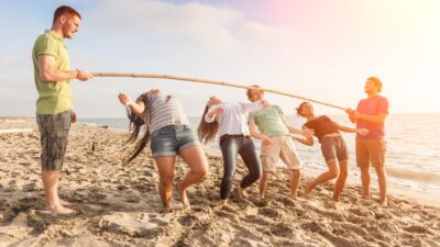 A group of six young people doing the limbo on a beach, indicating oversold shares that can not go any lower.