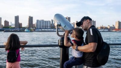 A father helps his son look through binoculars during a family holiday or day out in the city.