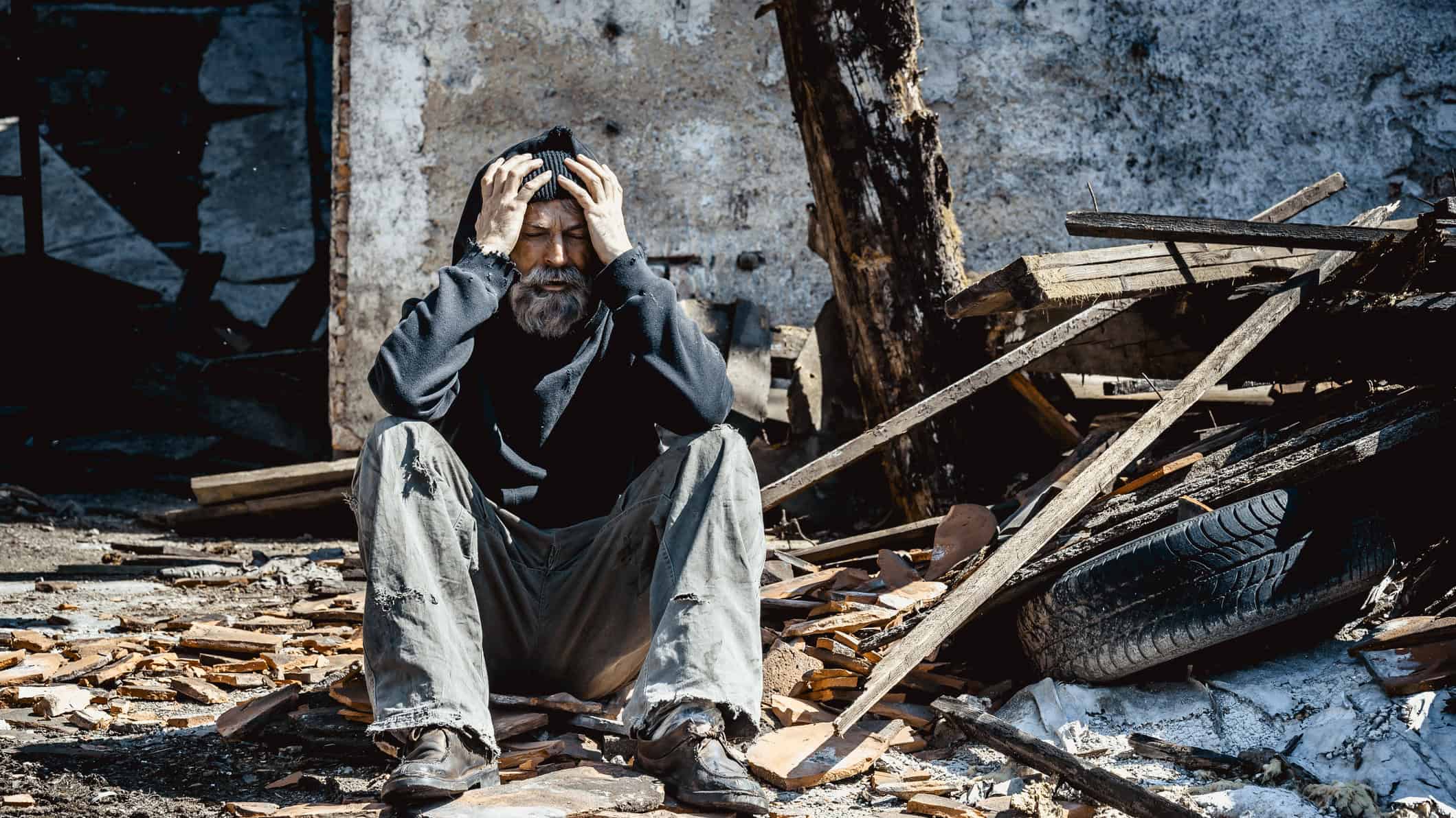 Homeless man on ruins of his house.