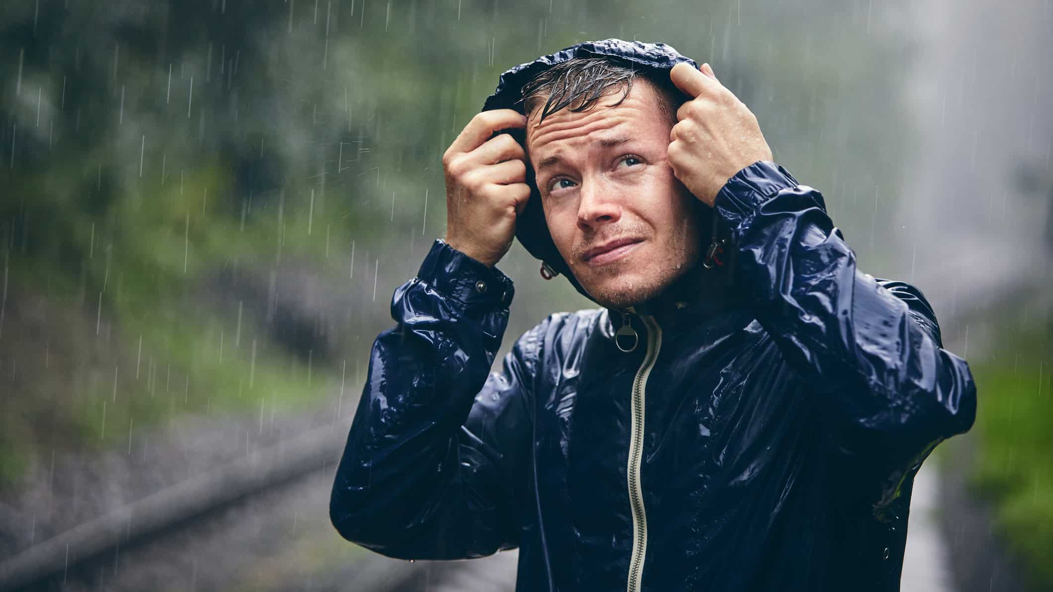 Man in drenched jacket in heavy rain.