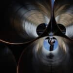 View of a mining or construction worker through giant metal pipes.