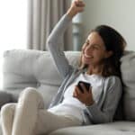 Ecstatic woman on her phone giving a fist pump after reading some good news.