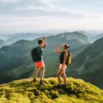 Two friends giving each other a high five at the top pf a hill.