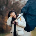 Woman with a broken umbrella walking in a storm and crying.
