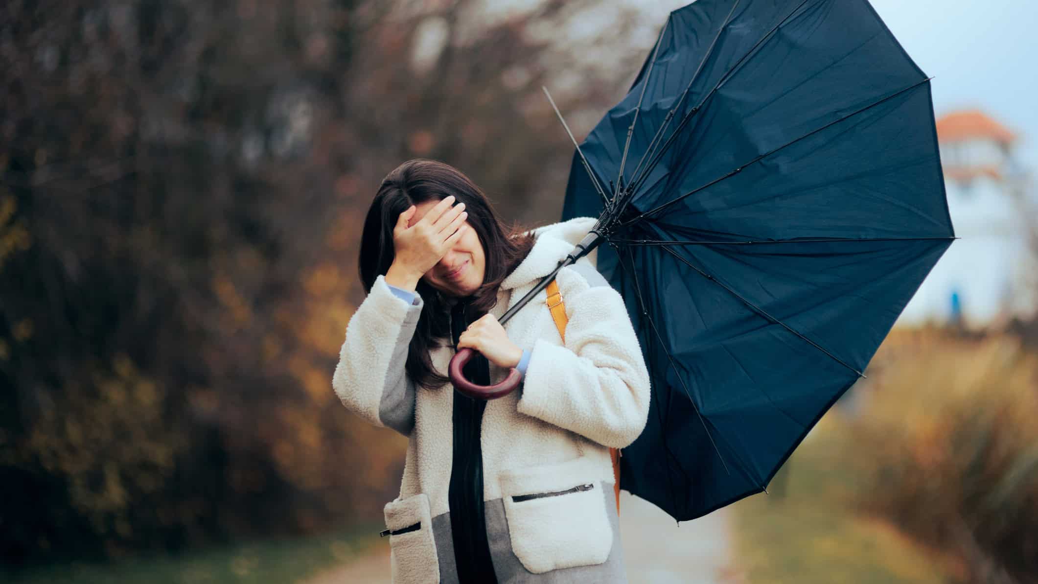 Woman with a broken umbrella walking in a storm and crying.