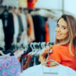 Cheerful girl deciding between tops in a stylish boutique.