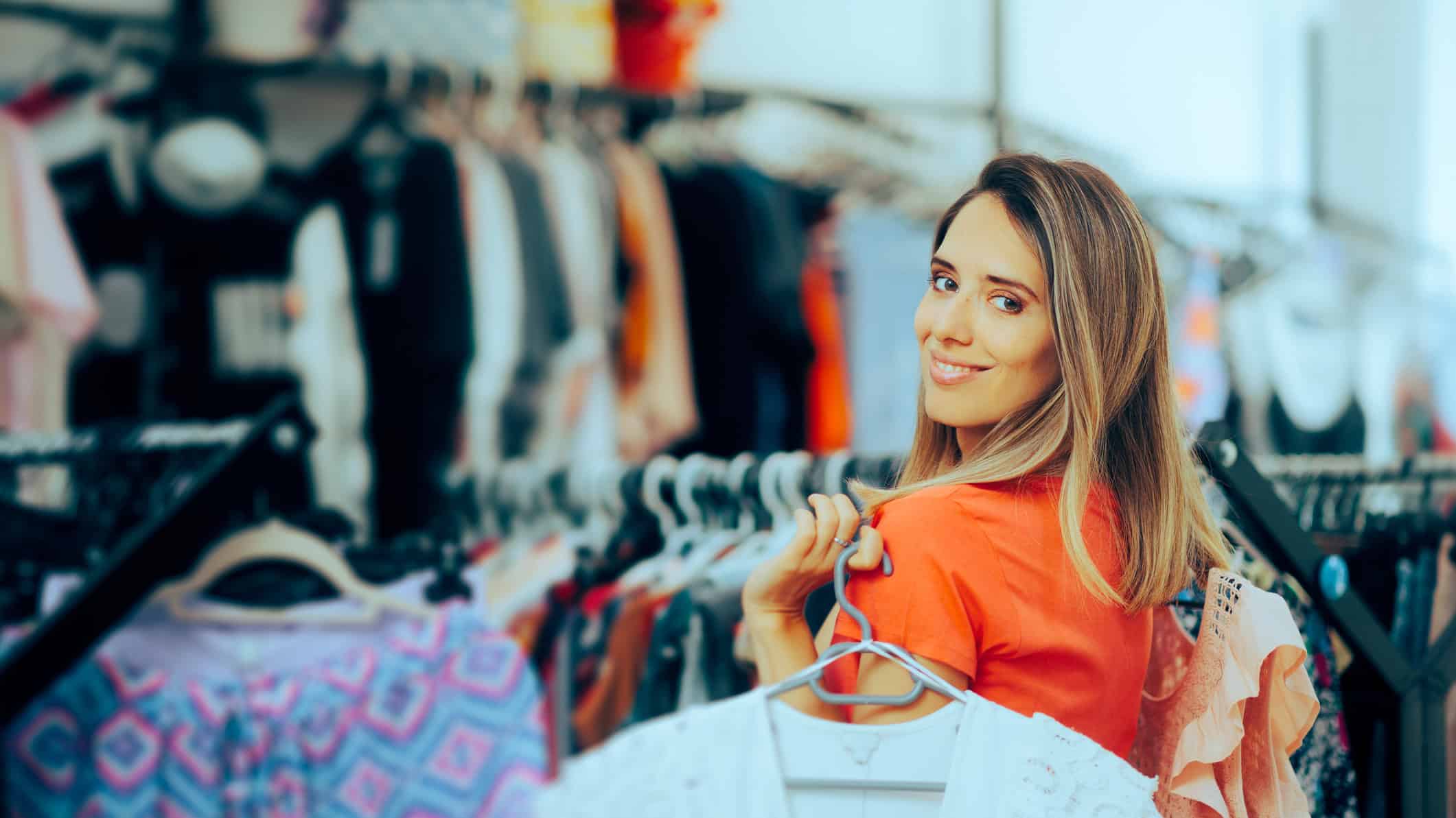 Cheerful girl deciding between tops in a stylish boutique.