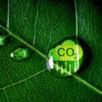 CO2 reducing icon on green leaf covered in a water droplet.