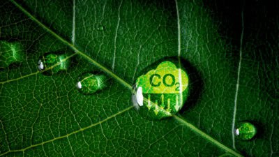 CO2 reducing icon on green leaf covered in a water droplet.