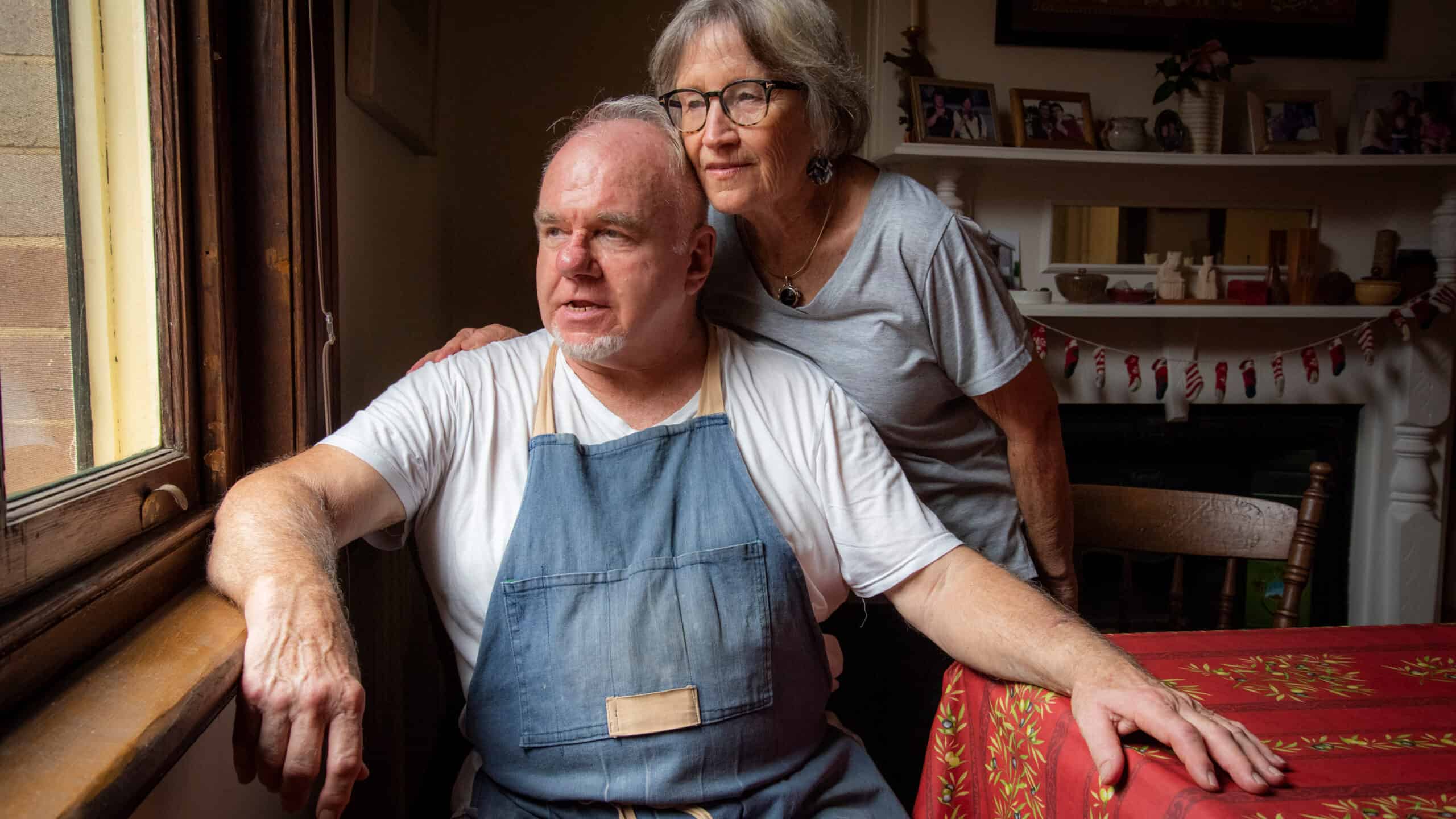 Two retirees looking through a window.