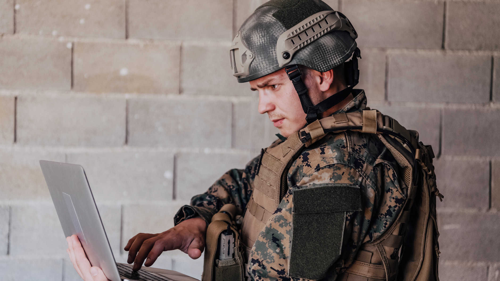 Soldier in military uniform using laptop for drone controlling.