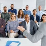 Large group of business people listening to their colleague giving them a speech in a board room.