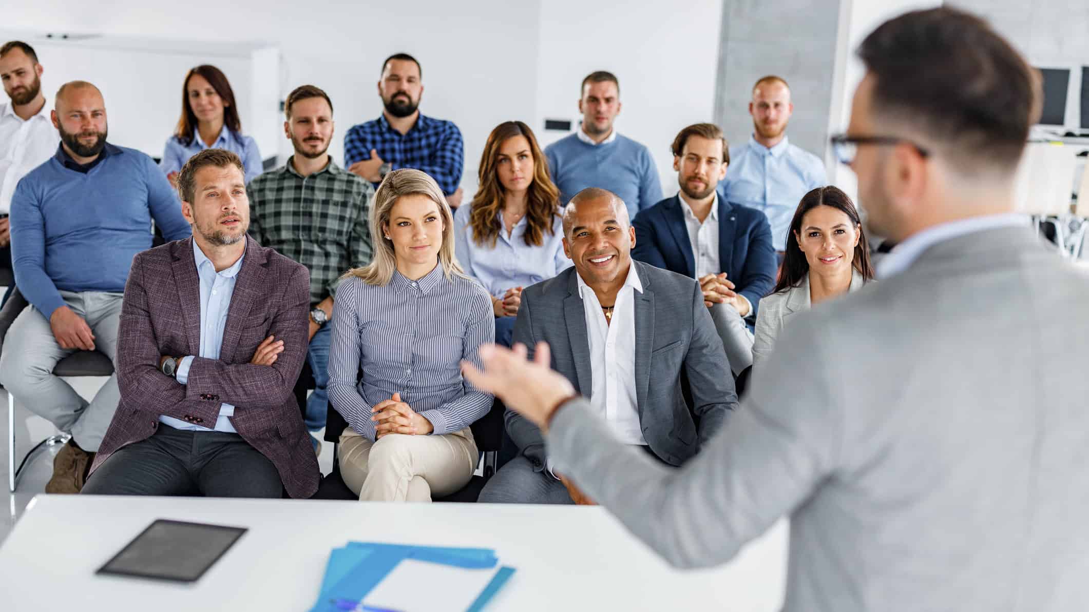 Large group of business people listening to their colleague giving them a speech in a board room.