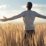Man with his arms spread wide in a field.