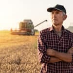Farmer with arms folded looking ahead.
